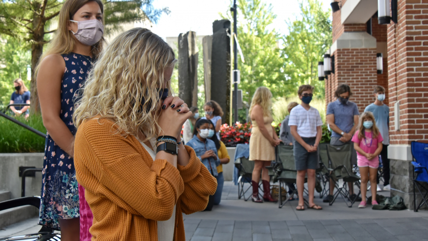 woman kneeling and praying at outdoor Mass