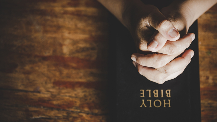 Bible with praying hands