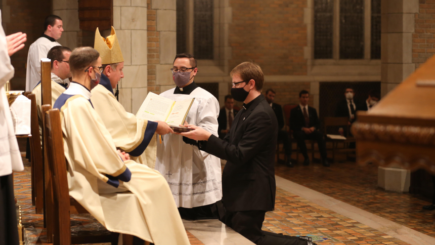 Bishop McClory hands Diocese of Gary seminarian (Zach Glick / Steven Caraher) a Bible at the Mass of Institution of Lectors and Acolytes at Sacred Heart 