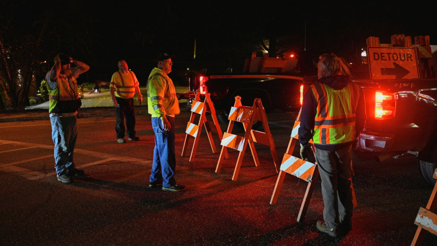 Workers set down detour signs while police organize around Lisbon High School in Lisbon Falls, Maine, Oct. 26, 2023, as an active search for a gunman is underway after deadly mass shootings. A man shot and killed at least 18 people and injured 13 others at a restaurant and a bowling alley in Lewiston, Maine, Oct. 25, and then fled into the night, sparking a massive search by hundreds of officers while frightened residents stayed locked in their homes. (OSV News photo/Nicholas Pfosi, Reuters)