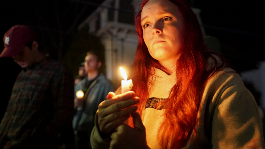 A woman holds a candle outside the Basilica of Sts. Peter and Paul in Lewiston, Maine, Oct. 29, 2023, during a vigil for the victims of a deadly mass shooting. Robert Card, who later took his own life, shot and killed 18 people and injured 13 others at a restaurant and a bowling alley in Lewiston Oct. 25. (OSV News photo/Kevin Lamarque, Reuters)