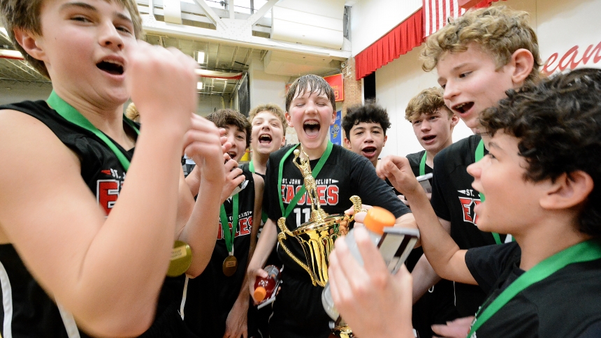 St. John the Evangelist Eagles players celebrate their team's victory in the 8th grade game of the Catholic Youth Organization boys basketball diocesan championships on Feb. 10 at Andrean High School in Merrillville. The Eagles soared past the Wildcats of St. Mary, Griffith, claiming a 48-41 victory and the title trophy to cap off their last year at the St. John school. (Anthony D. Alonzo photo)