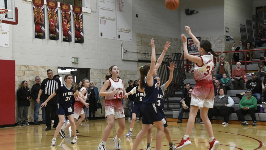 St. Michael the Archangel player Adriana Dabrowski (right) takes three-point shot over St. Mary Catholic Community School of Crown Point defenders during the sixth-grade game of the girls Catholic Youth Organization basketball championships hosted at Andrean High School on March 17. (Anthony D. Alonzo photo) 