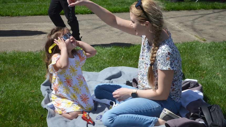 Maria Diaz instructs her daughter Mila, 2, to look toward the sun and see the beginning of the solar eclipse on April 8. The Diaz family was one of many families who took advantage of the invitation by Nativity of Our Savior School to watch the event together as a community on the school's grounds. (Erin Ciszczon photo)